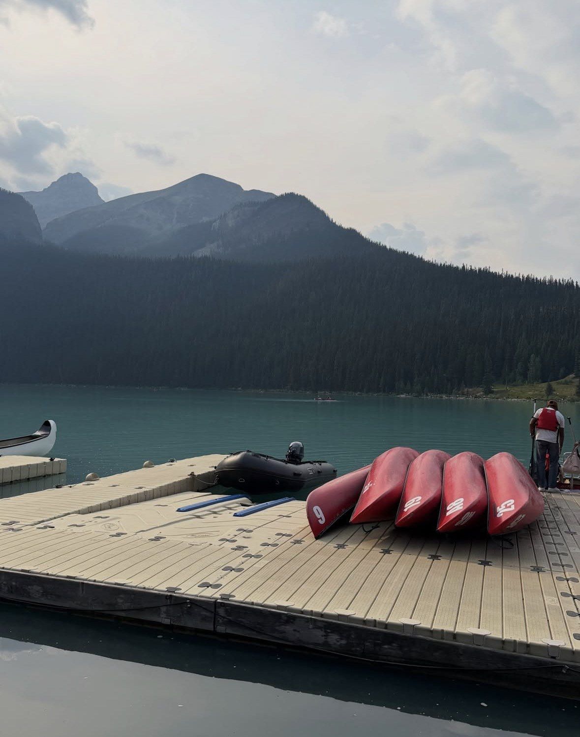 Red canoes stacked on the Lake Louise dock under hazy morning sky